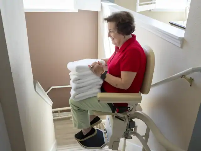 Woman with towels on her lap on a stairlift
