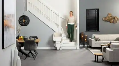 Woman decends stairs beside a parked modular curved stairlift