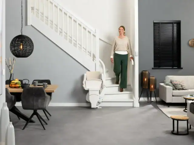 Woman decends stairs beside a parked modular curved stairlift