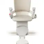 A beige and white stairlift chair with armrests and a footrest, mounted on a rail, shown from the front against a white background.