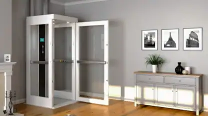 A home elevator with open doors is installed in a modern living room with wooden flooring, a rug, a sideboard, and framed photos on a gray wall.